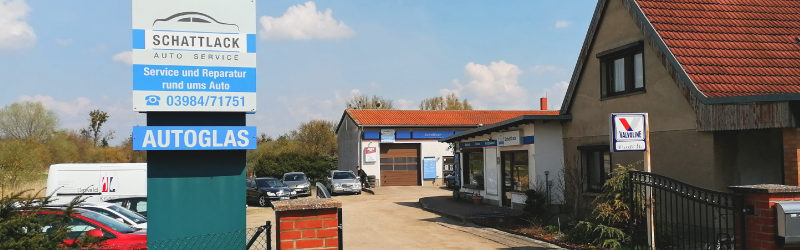 Einfahrt zur Werkstatt am Rohrteich mit Schild „Schattlack Auto Service, Autoglas“ und Werkstattgebäude